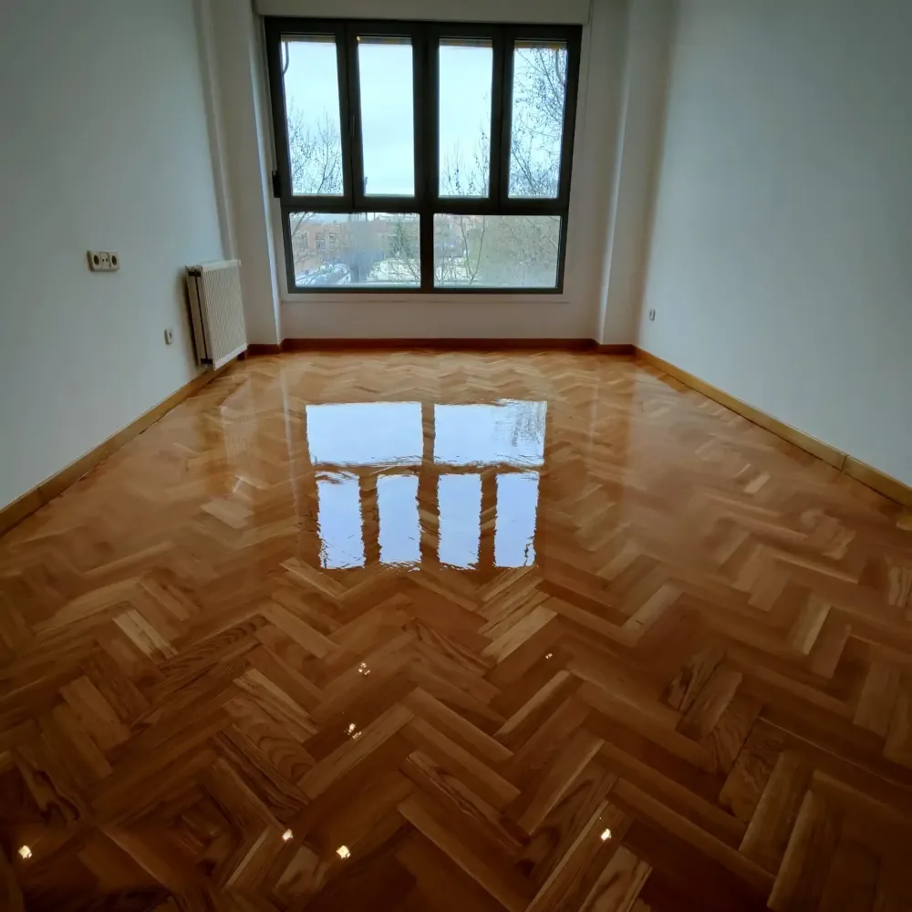 Salón con parquet en espiga barnizado junto a un ventanal
