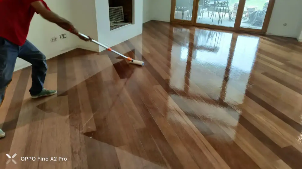 Aplicación de barniz sobre un suelo de madera durante el acuchillado
