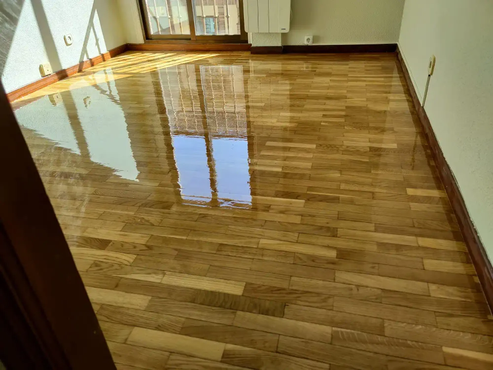 Suelo de parquet en espiga barnizado reflejando la luz natural del ventanal